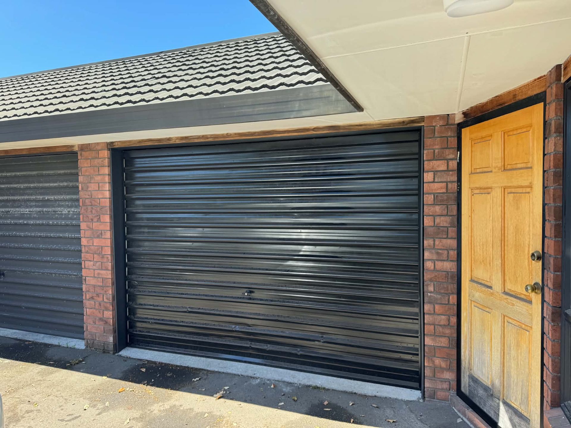 Black roller garage door with brick surround