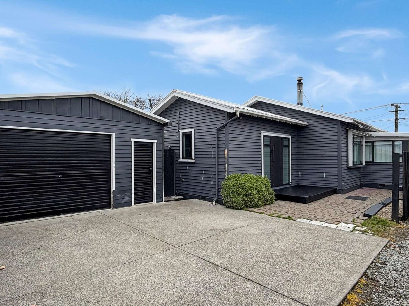 Dark grey repainted weatherboard home with black garage doors